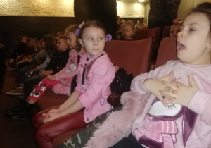 dzieci siedzą w sali kinowej